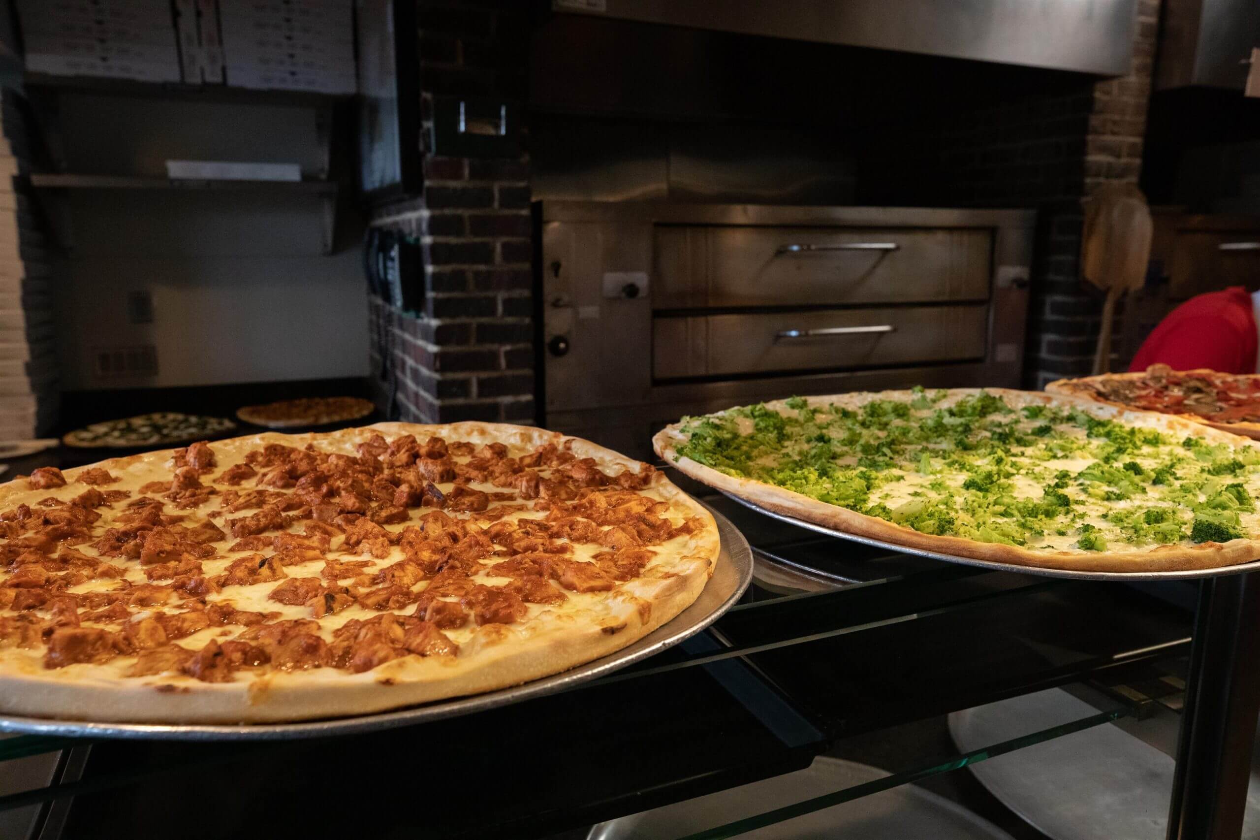 a LONG SHOT OF THE LARGE CHICKEN AND BROCCOLI PIZZAS